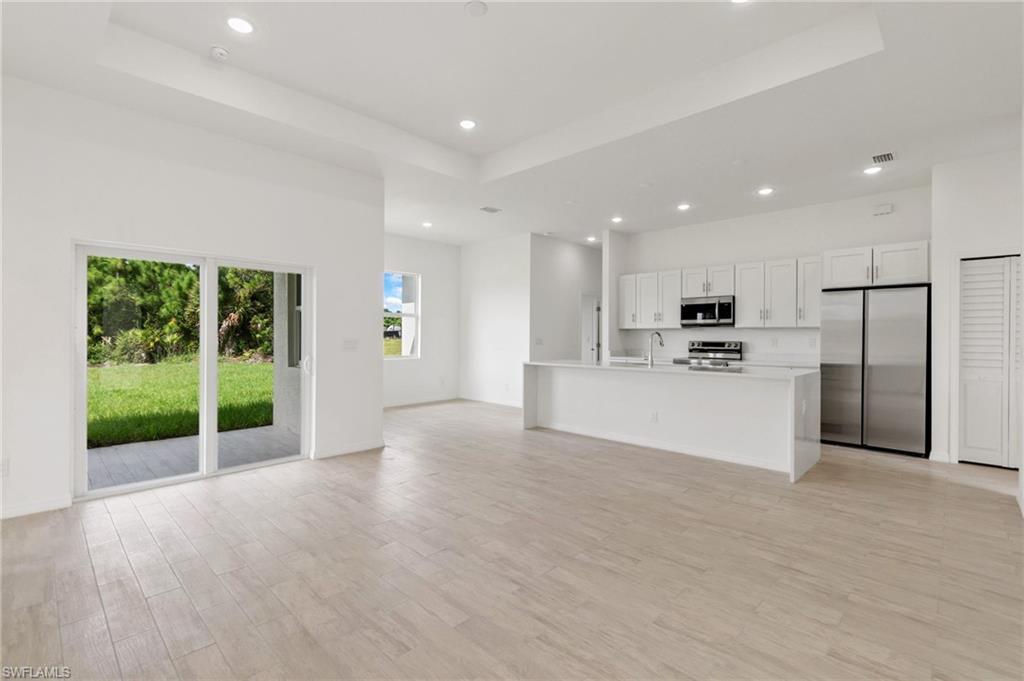 a view of kitchen with stainless steel appliances kitchen island wooden floor and window