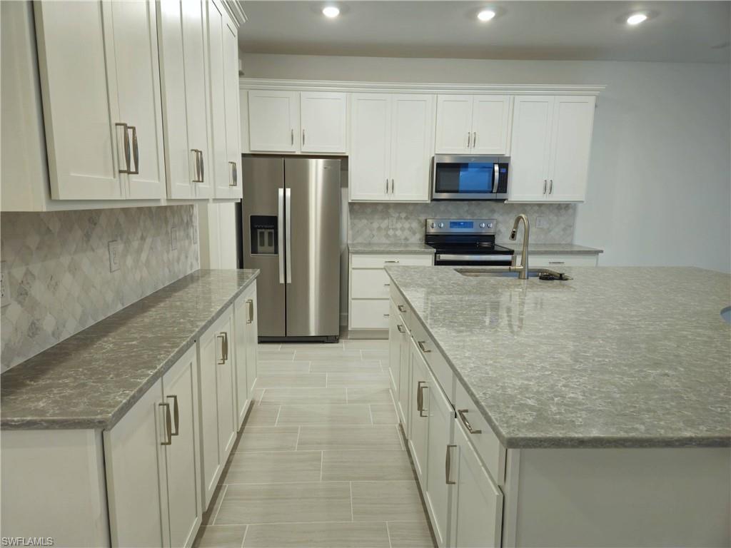 a kitchen with stainless steel appliances granite countertop a stove a sink and a refrigerator