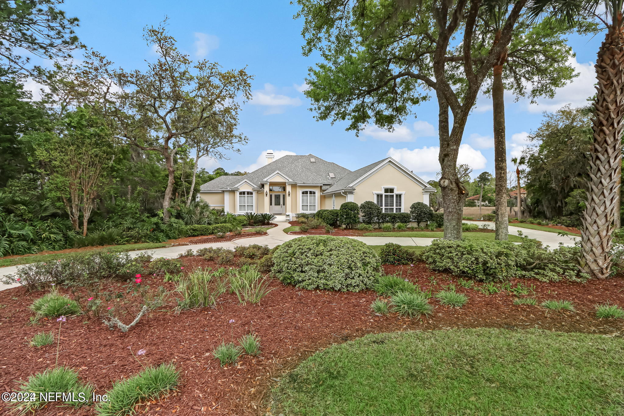 a front view of a house with a yard and large trees