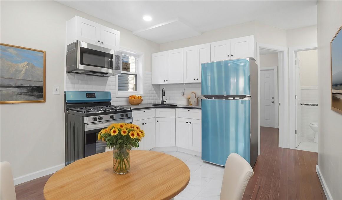 Kitchen featuring backsplash, white cabinetry, sink, light hardwood / wood-style floors, and stainless steel appliances