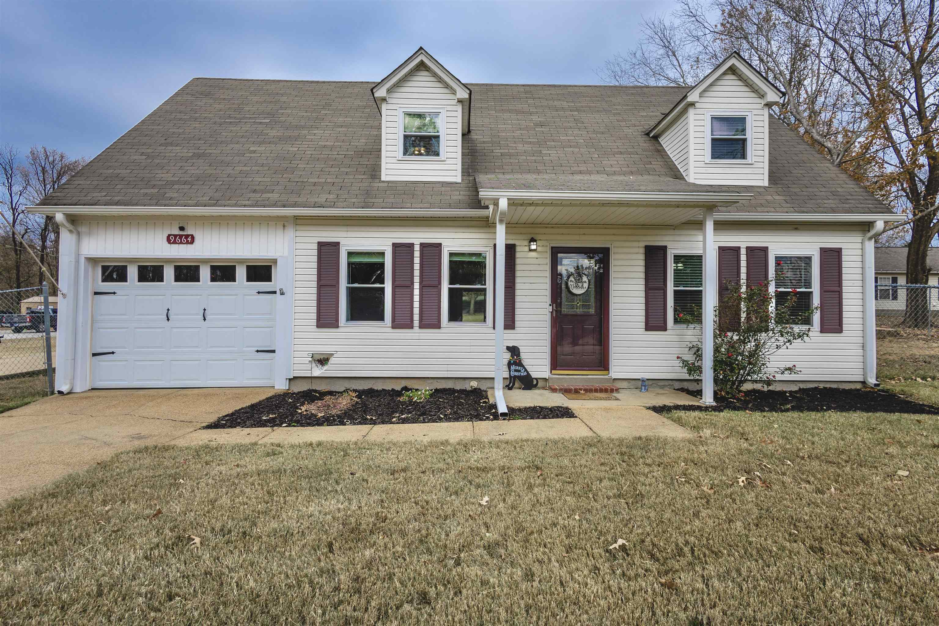 Cape cod-style house featuring a garage and a front lawn