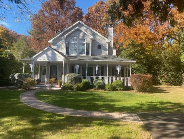 Farmhouse-style home with covered porch and a front lawn