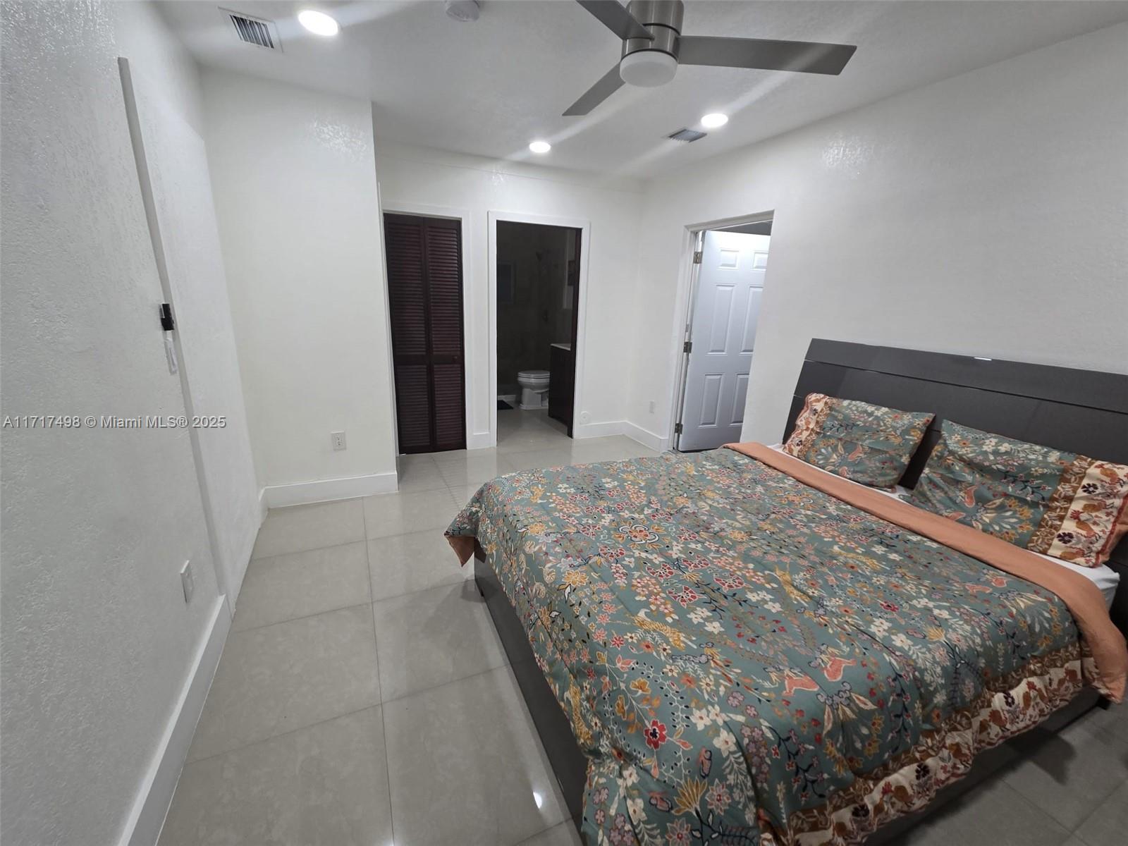 a bedroom with a large bed and ceiling fan