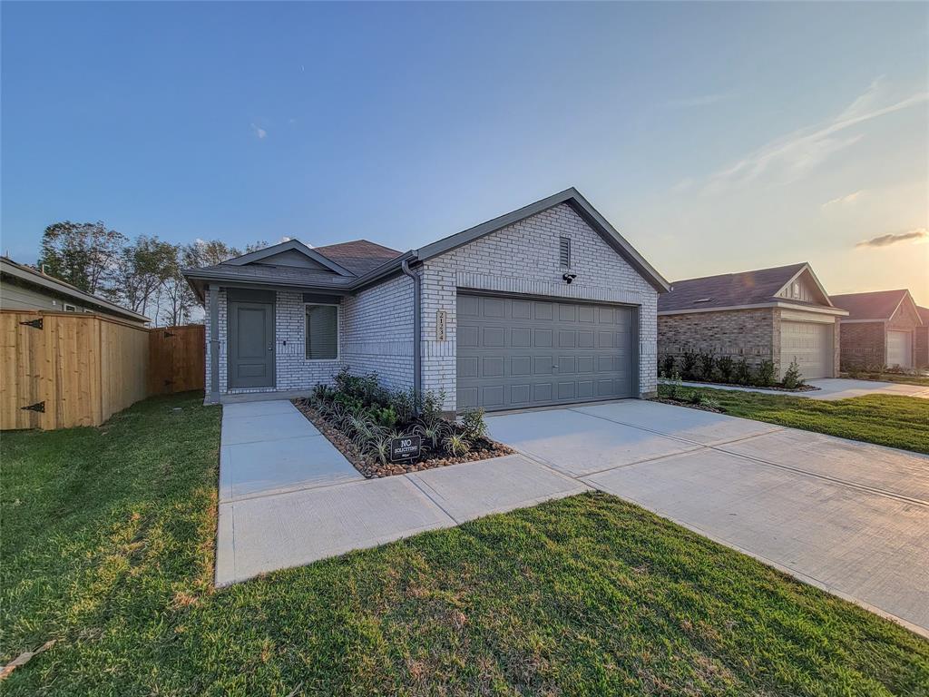 This is a single-story home featuring a brick exterior with an attached two-car garage, a neatly landscaped front yard, and a new wooden privacy fence along the side.