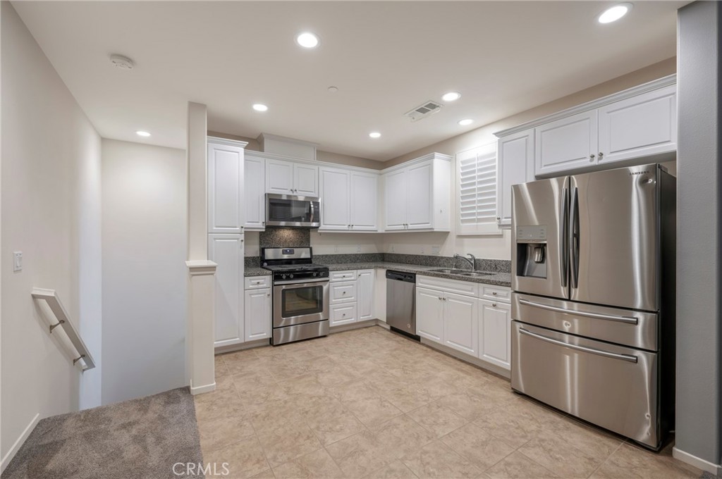 a kitchen with granite countertop stainless steel appliances and refrigerator