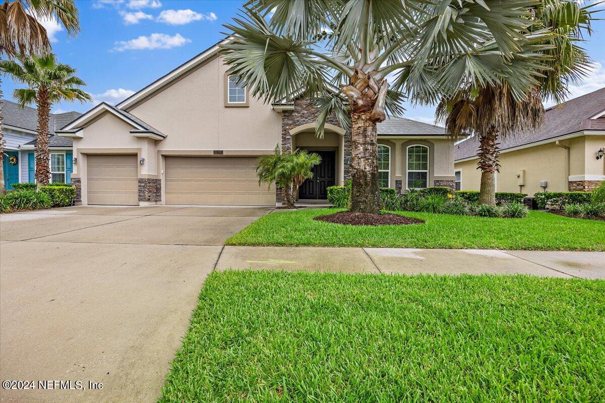 a front view of a house with a garden and palm trees