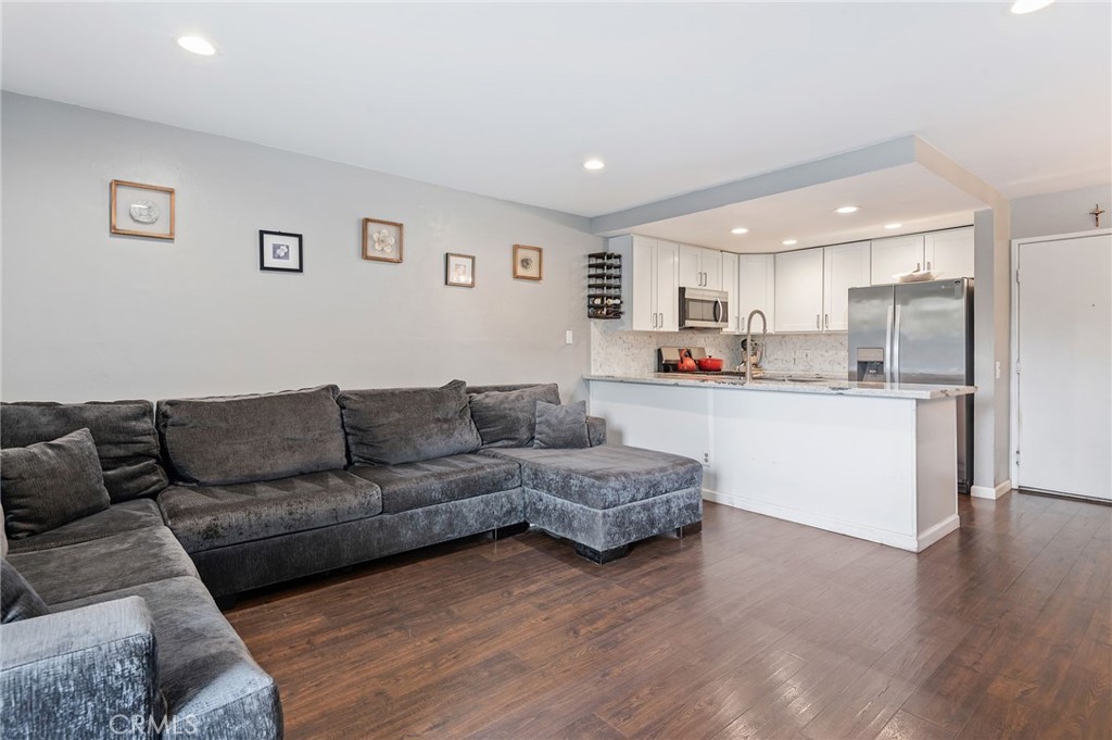 a living room with stainless steel appliances kitchen island granite countertop a couch and cabinets