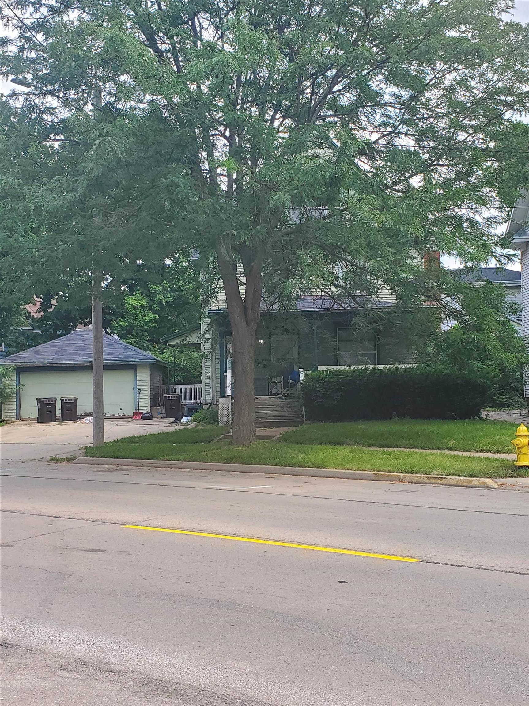 a view of a house with a yard and large trees