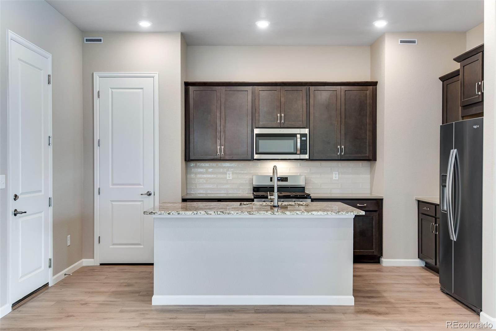 a kitchen with kitchen island granite countertop appliances cabinets and a counter top space