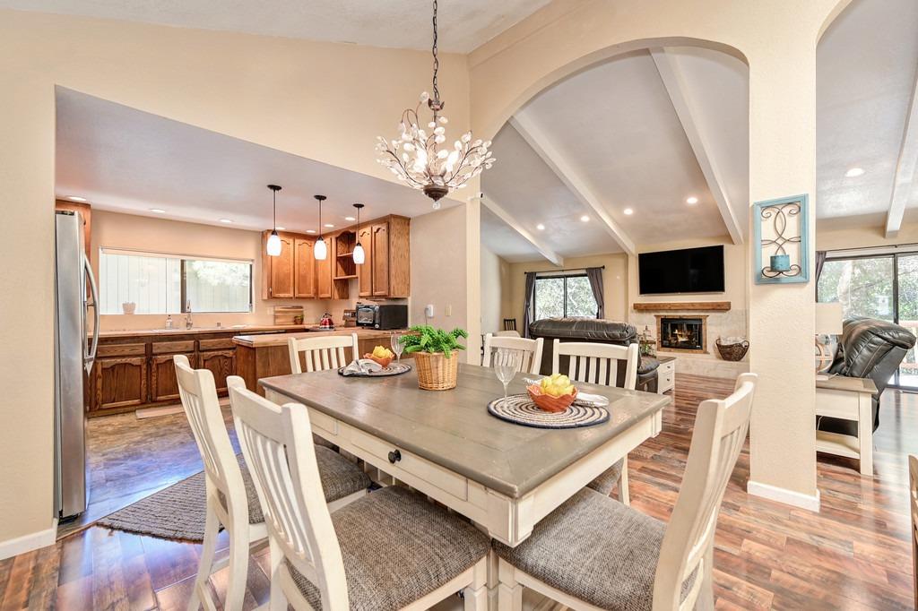 a view of a dining room and livingroom with furniture wooden floor a rug a flat screen tv a rug and a chandelier