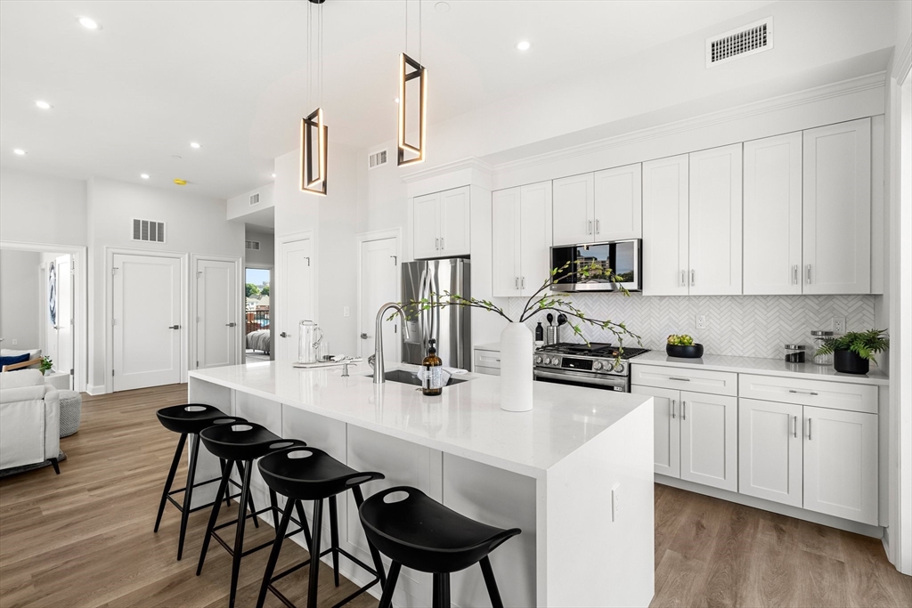 a kitchen with stainless steel appliances a sink a stove a table and chairs