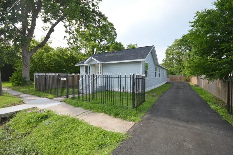 a view of a house with a small yard plants and large trees