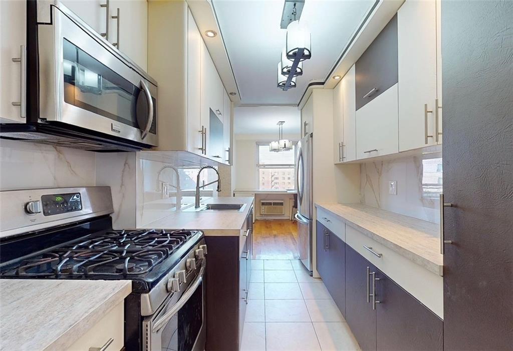 a kitchen with stainless steel appliances granite countertop a stove a sink and a microwave