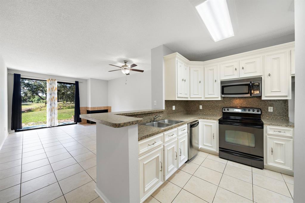 a kitchen with stainless steel appliances granite countertop a stove top oven a sink dishwasher and a refrigerator