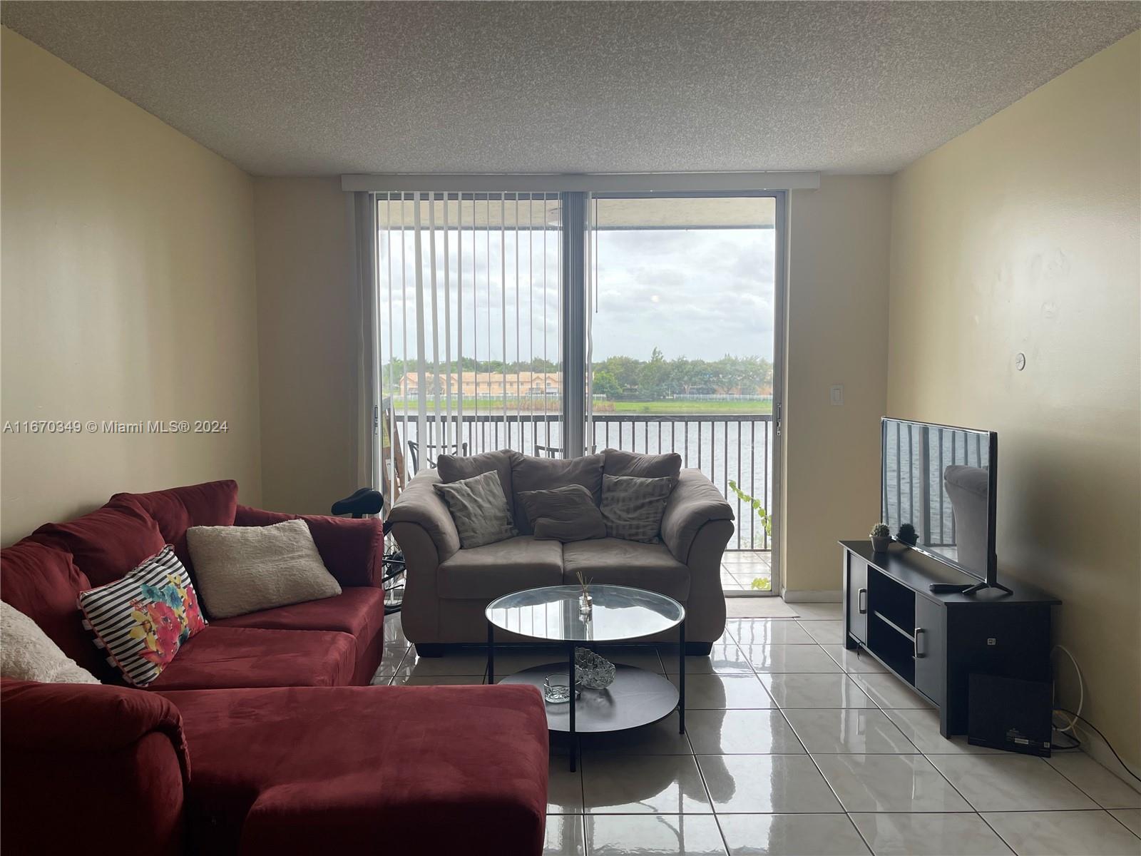 a living room with furniture a flat screen tv and a large window