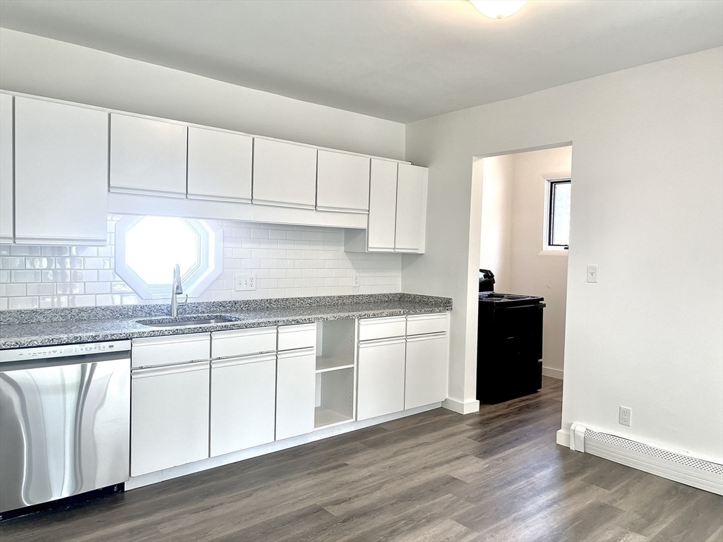 a kitchen with granite countertop white cabinets and sink