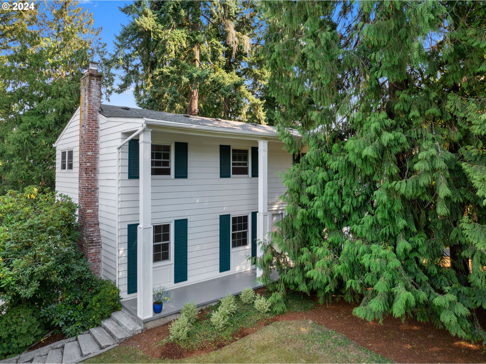 a front view of a house with plants and trees