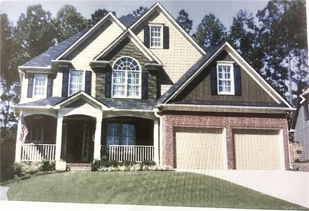 View of front facade with a porch, a front yard, and a garage