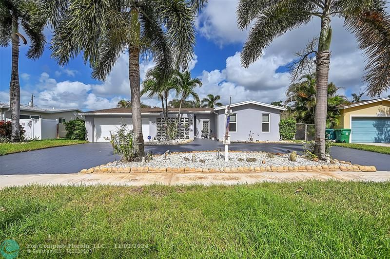 front view of house with a yard and palm trees