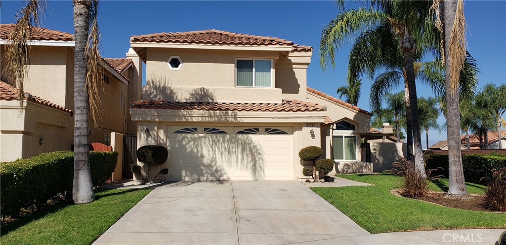 a view of a house with a small yard and a large tree