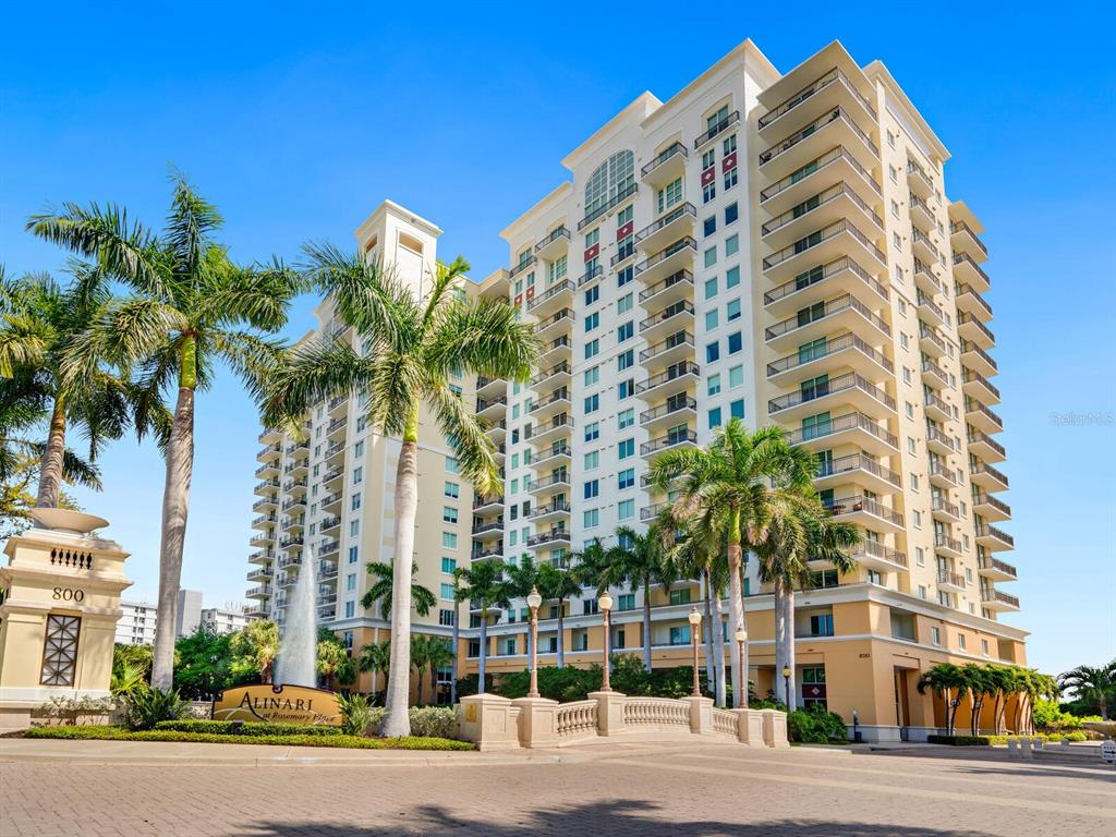 a front view of multi story residential apartment building with yard and parking space