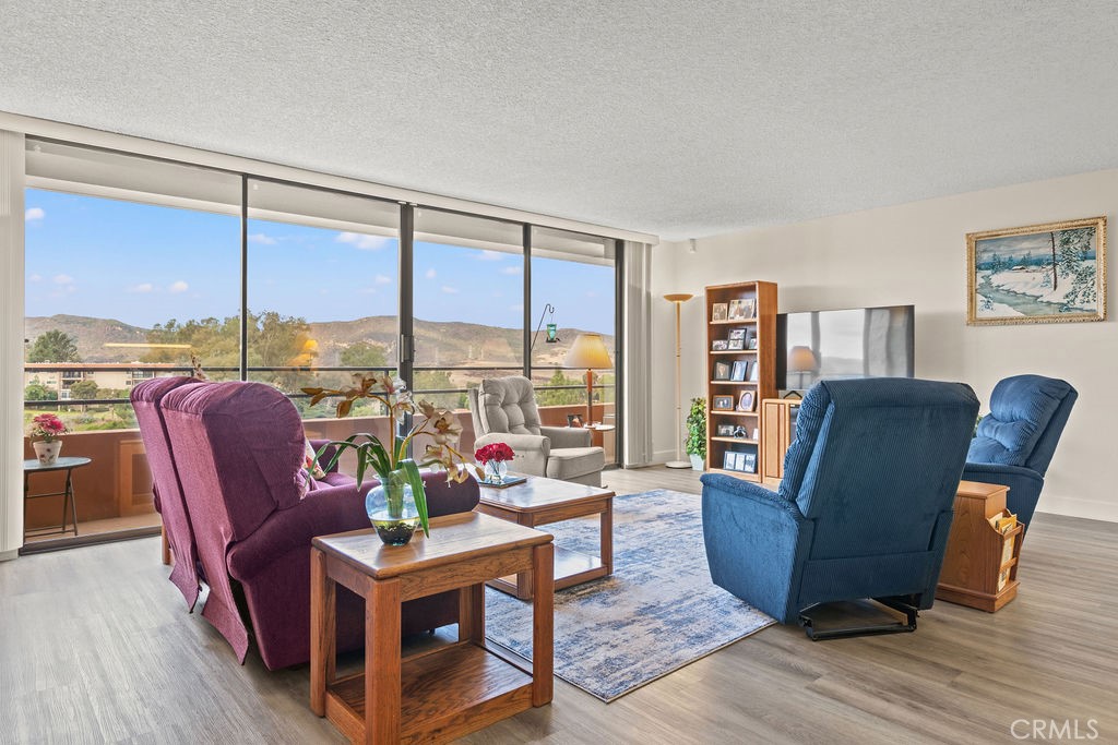 a living room with furniture large windows and wooden floor