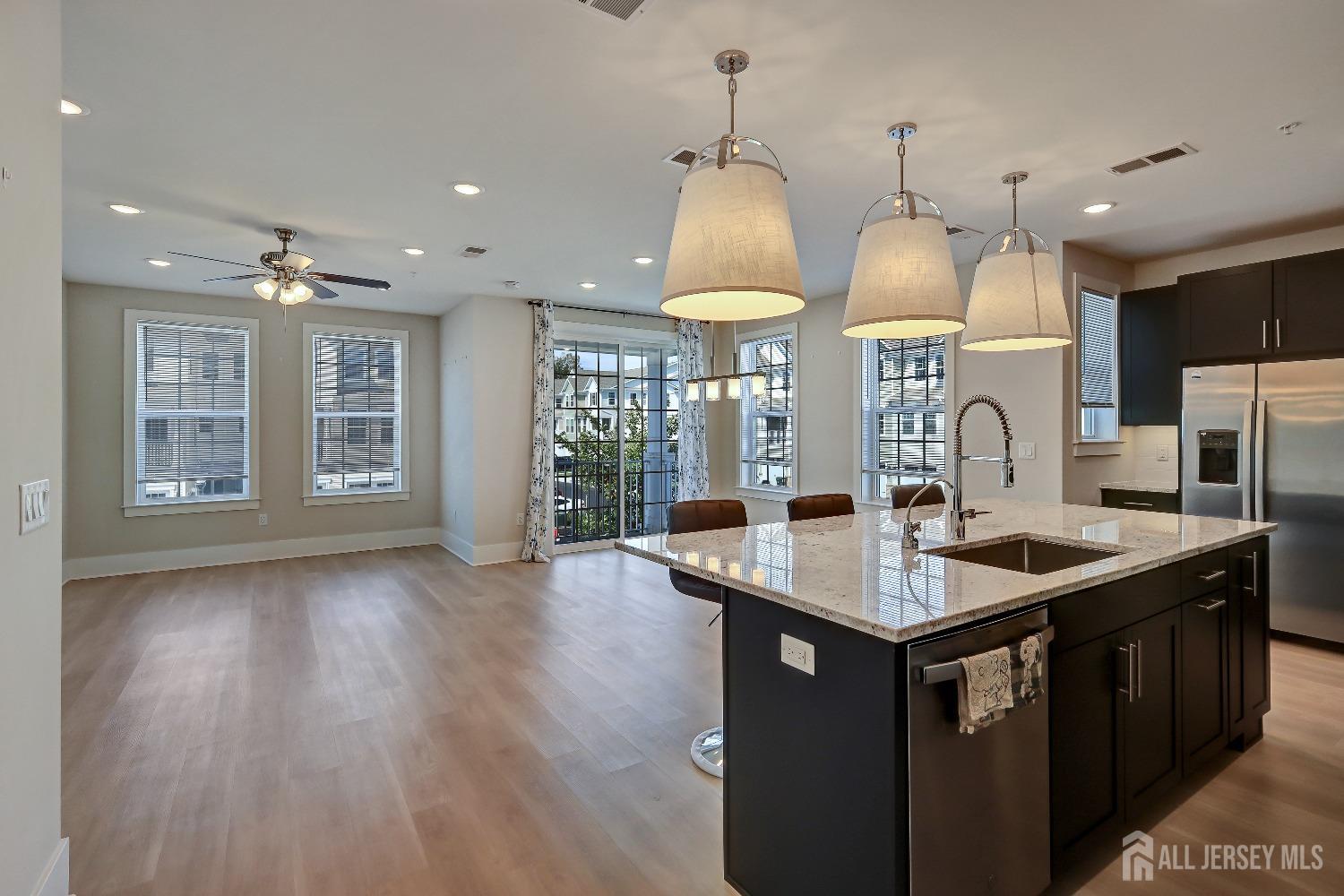 a kitchen with stainless steel appliances granite countertop a sink a stove and a wooden floors