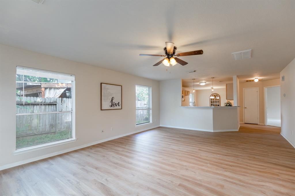 a view of an empty room with window and wooden floor