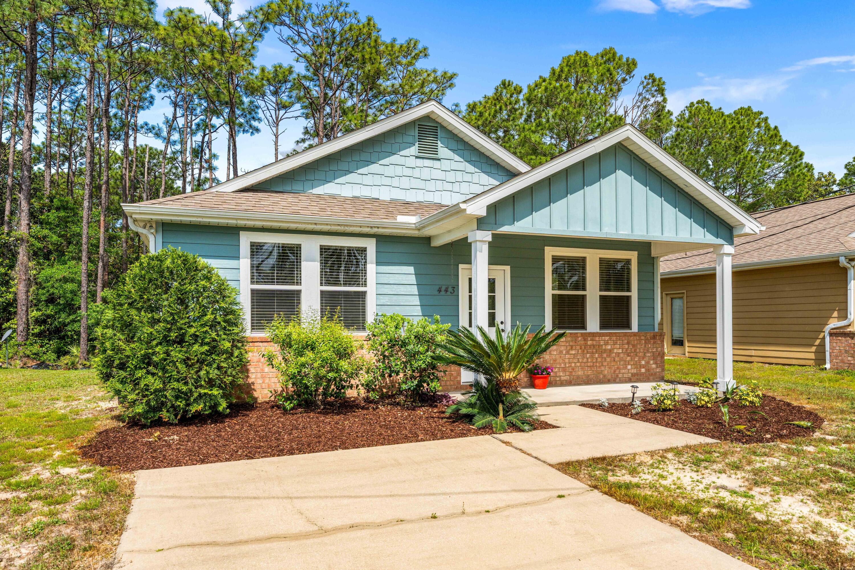 a front view of a house with a yard and potted plants