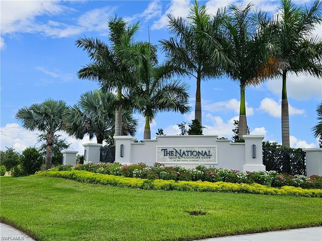 a view of a sign in front of a house with a big yard and large trees