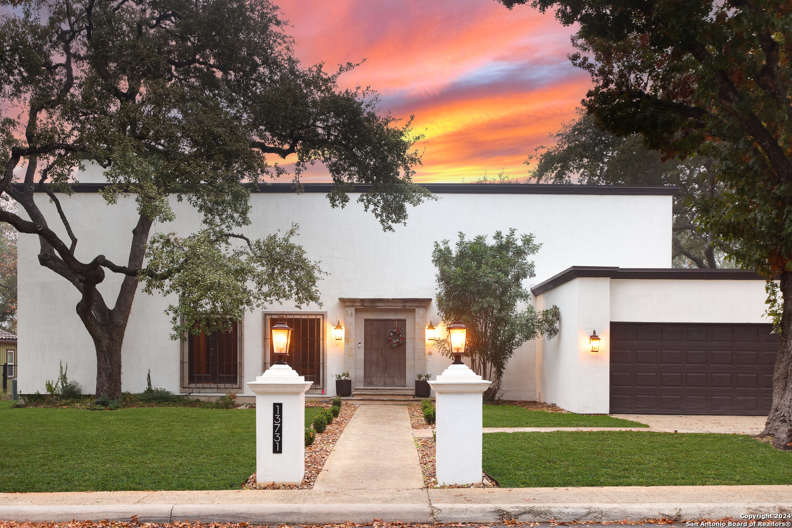 a front view of a house with garden and trees