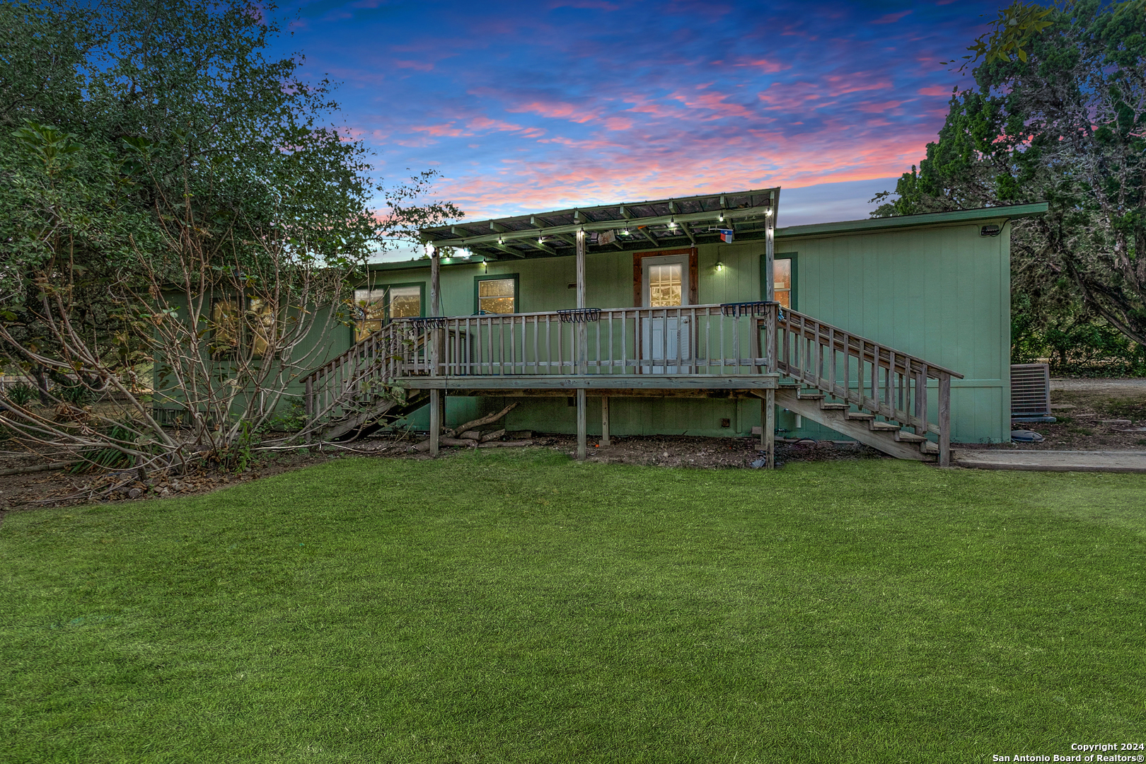 a view of a house with a backyard and a wooden deck