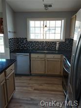 Kitchen with backsplash, wood-type flooring, black refrigerator with ice dispenser, and stove