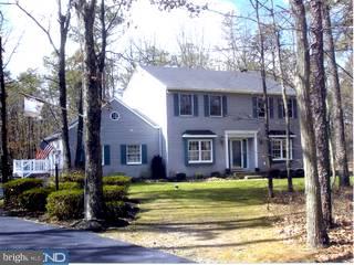 a view of a brick house next to a yard with large trees