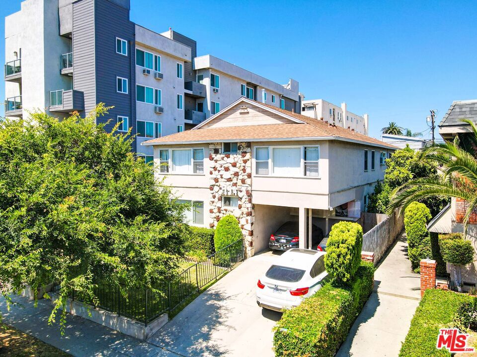 a front view of a multi story residential apartment building with yard and parking space