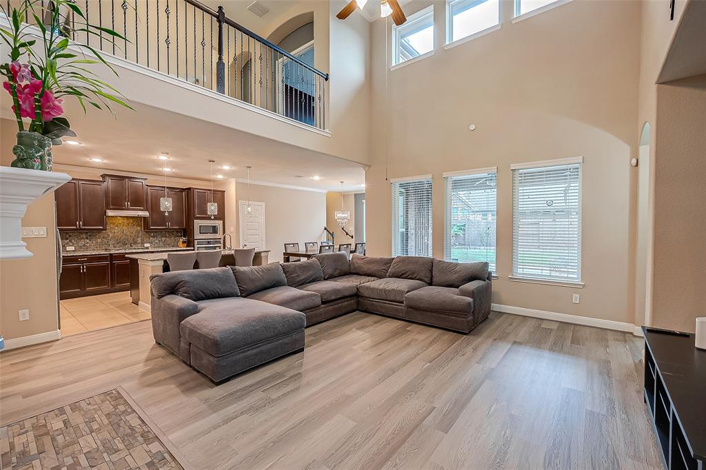 Stunning interior! This open-concept design features a grand family room with a wall of windows, filling the space with natural light and creating an inviting atmosphere perfect for entertaining family and friends. Enjoy a beautiful view of the upstairs balcony, highlighted by an elegant wrought-iron railing.