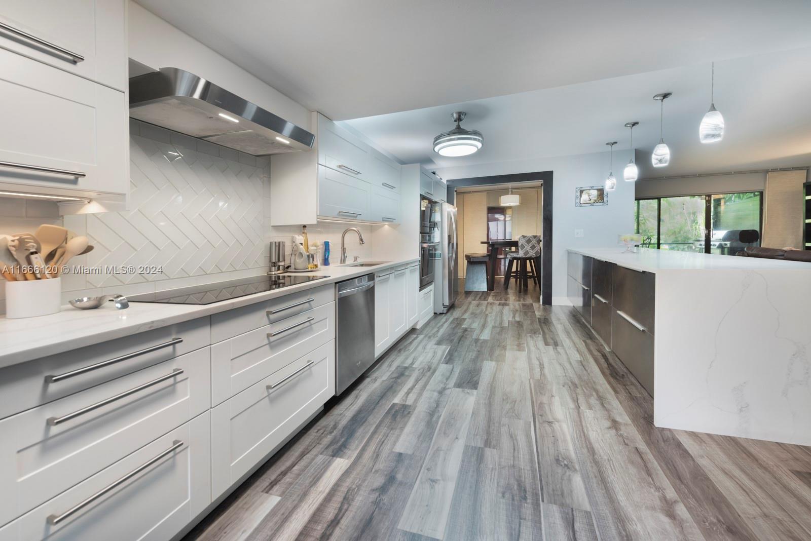 a large kitchen with cabinets wooden floor and stainless steel appliances