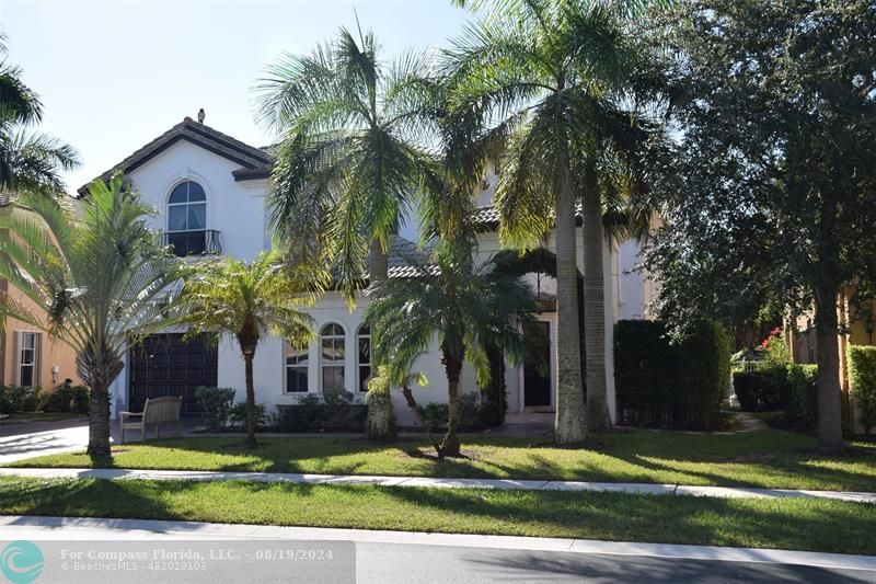 a view of a house in a big yard with palm trees