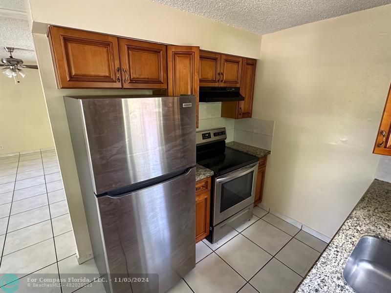 a kitchen with stainless steel appliances granite countertop a refrigerator and a stove