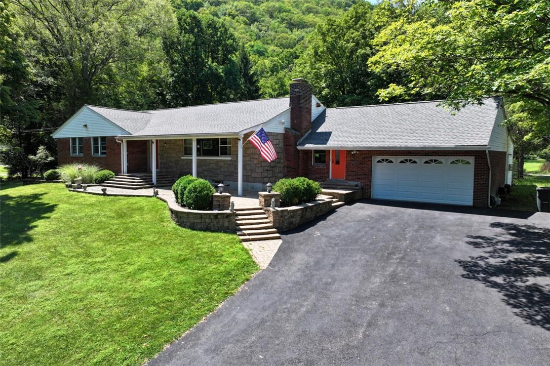 Ranch-style house featuring a porch, a garage, and a front yard