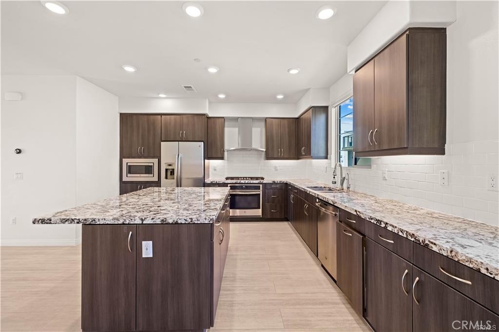 a large kitchen with stainless steel appliances kitchen island granite countertop a large counter top and a stove top oven