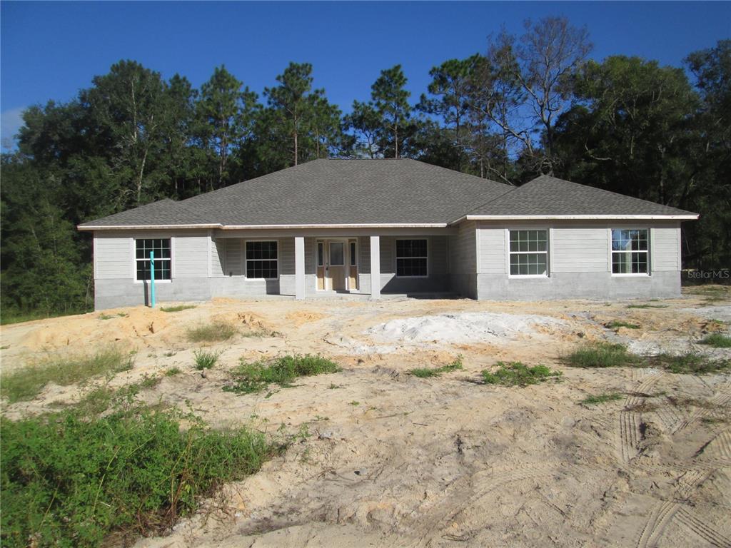 a front view of a house with a yard covered with trees