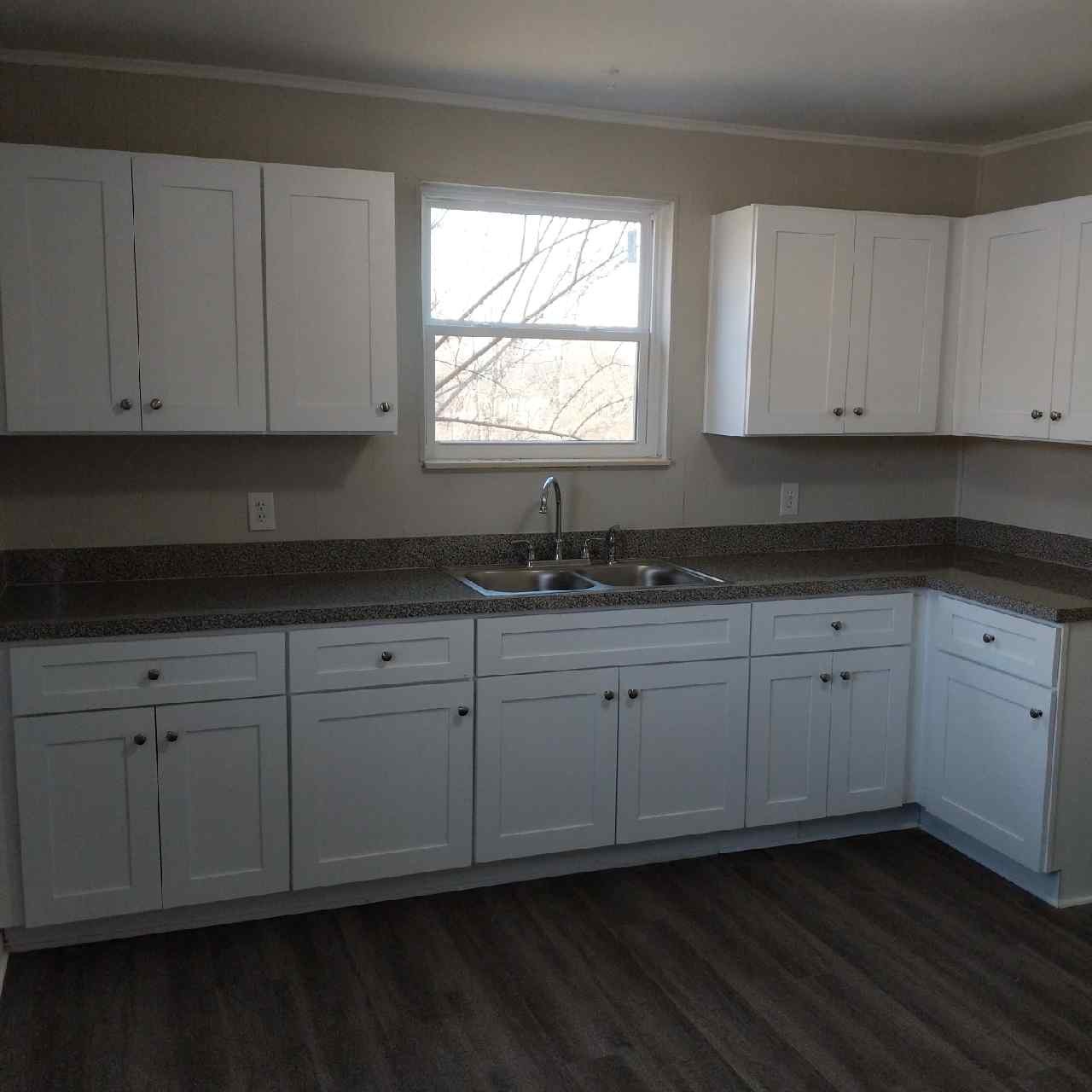 a kitchen with granite countertop white cabinets sink and window