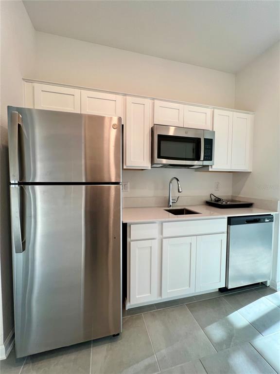 a kitchen with stainless steel appliances granite countertop a refrigerator a microwave a sink and a stove