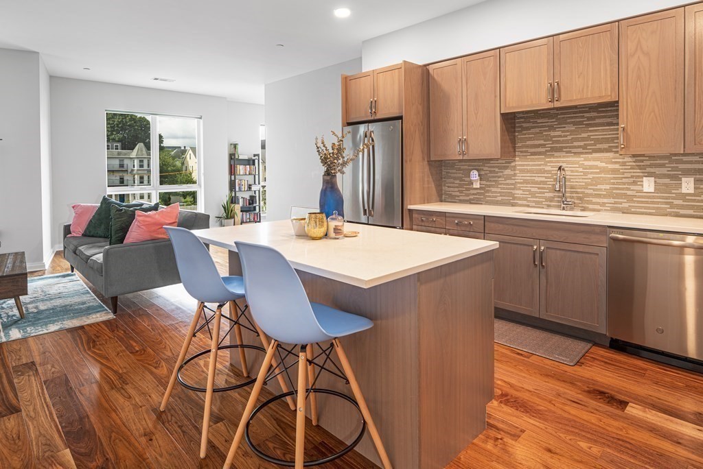 a open kitchen with stainless steel appliances granite countertop a stove a sink dishwasher and a refrigerator with wooden cabinets