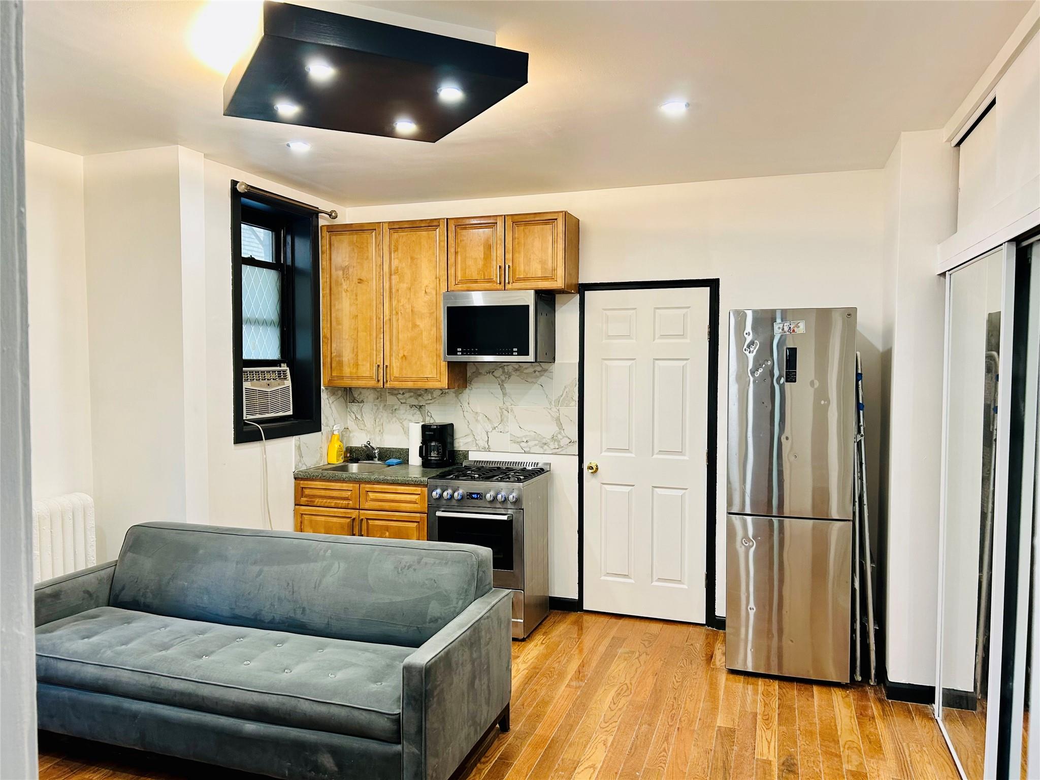 Kitchen with radiator, stainless steel appliances, tasteful backsplash, light hardwood / wood-style flooring, and cooling unit