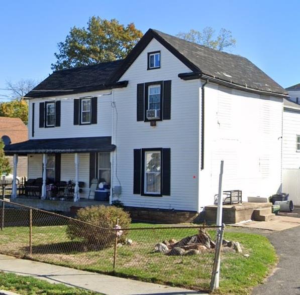 View of front of house featuring cooling unit, covered porch, and a front yard