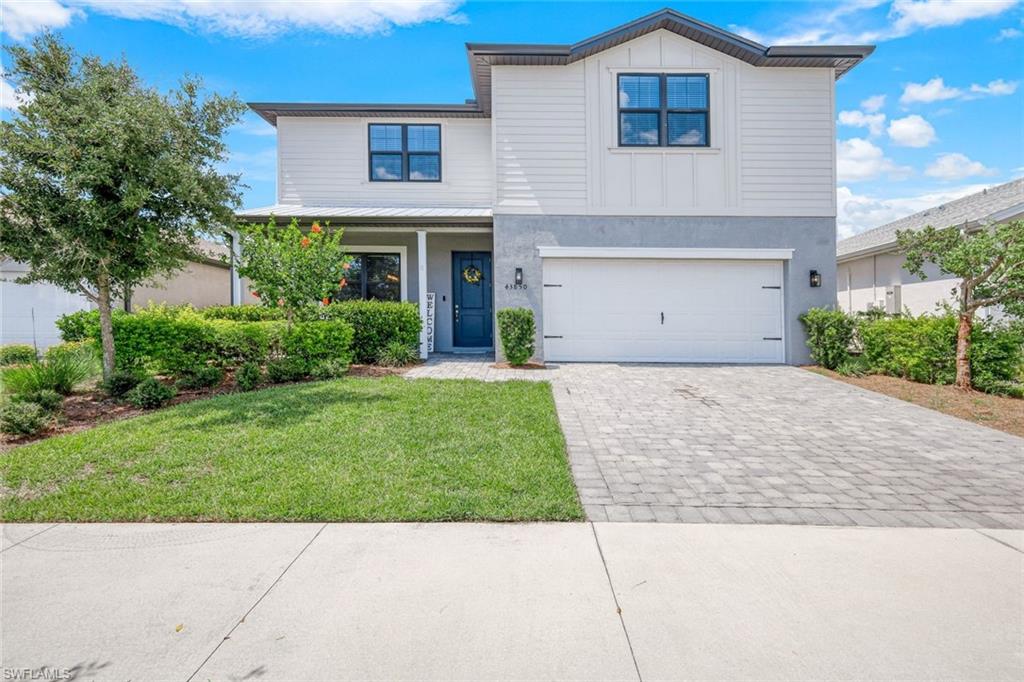 View of front of property featuring a garage and a front lawn