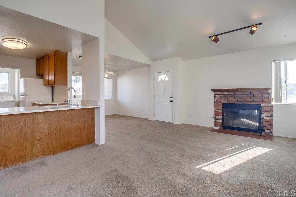 a view of kitchen and empty room with fireplace