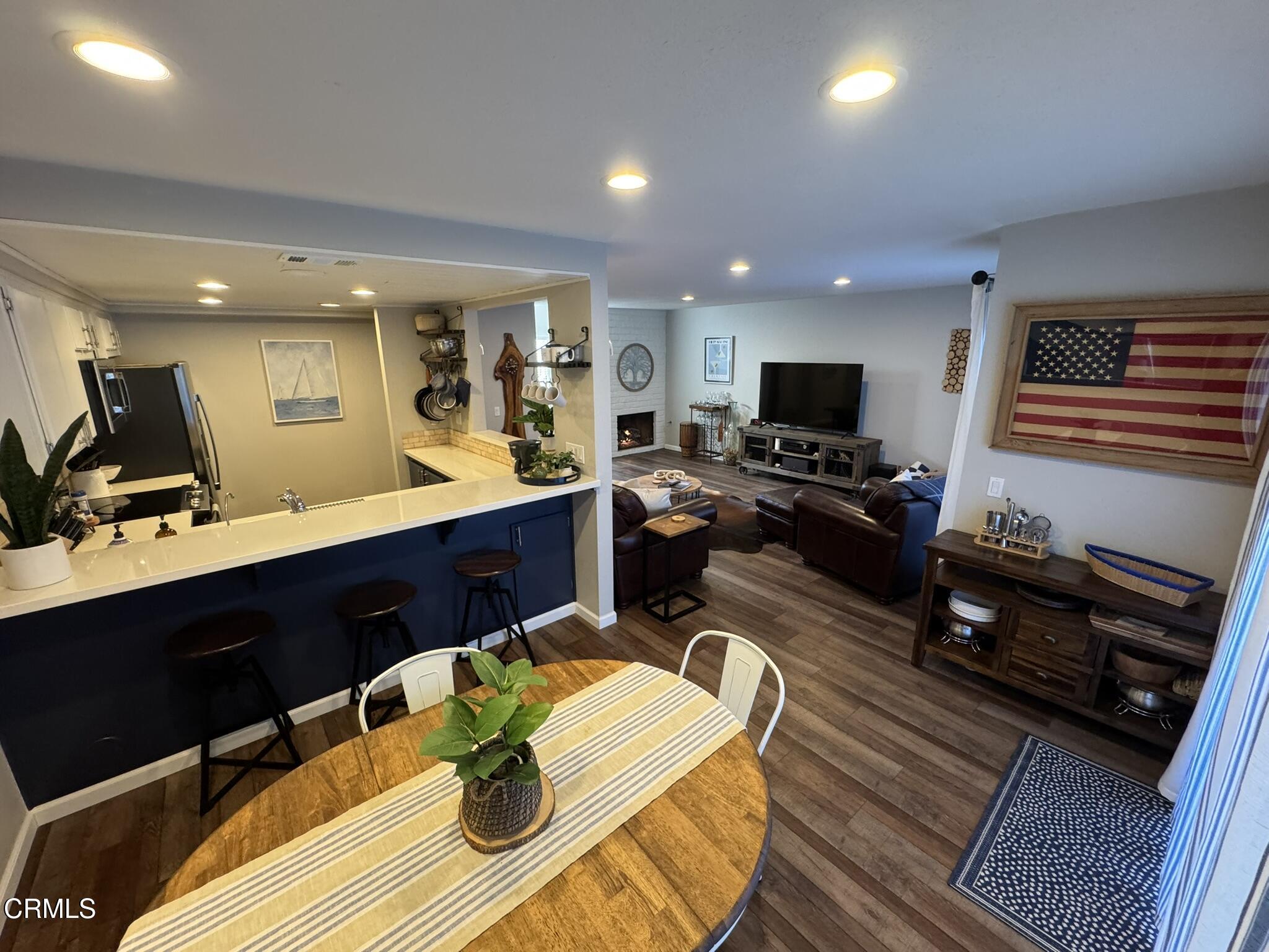 a living room with couches a flat screen tv and kitchen view